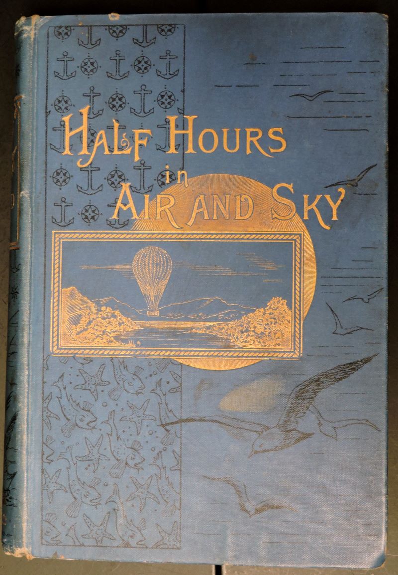 Picture of book cover in blue cloth showing a balloon in the sky beneath the title, all in gilt.